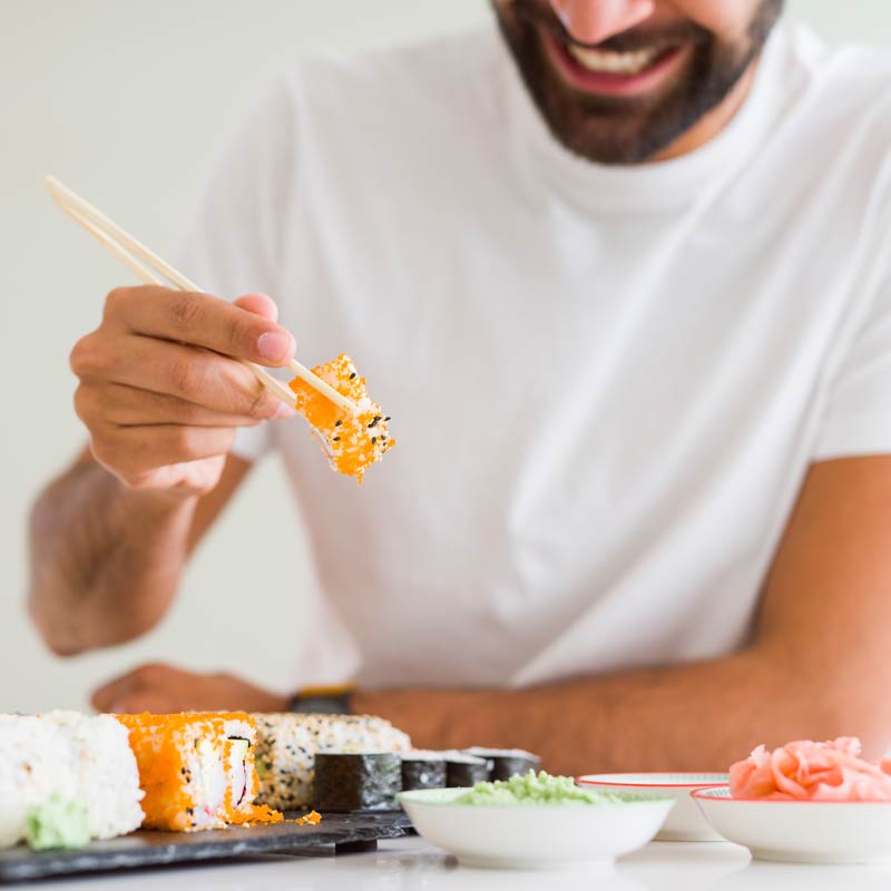 Man using chopsticks to eat sushi