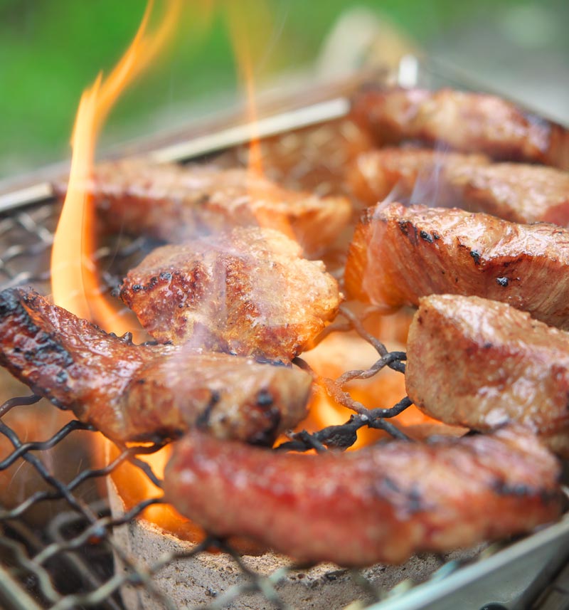 Japanese yakiniku meat being grilled on a charcoal barbecue
