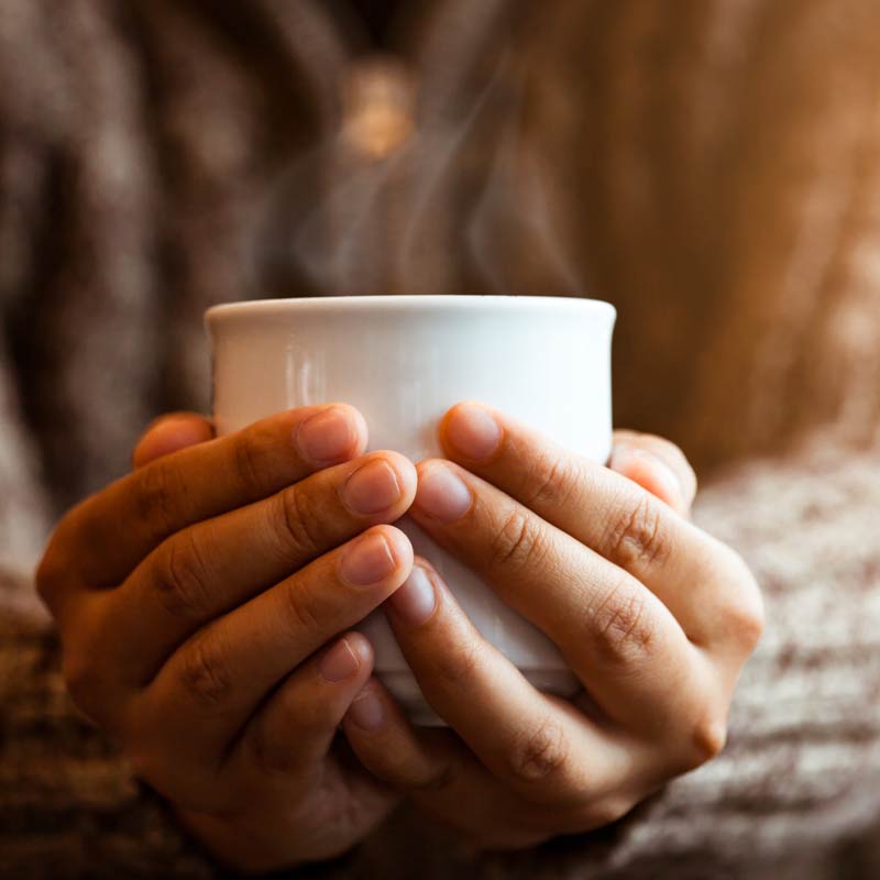 Hands holding a warming cup of tea