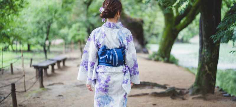 Japanese woman dressed in a yukata strolling in a park