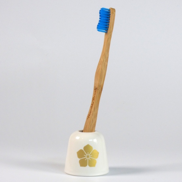 White ceramic toothbrush holder with gold samurai crest