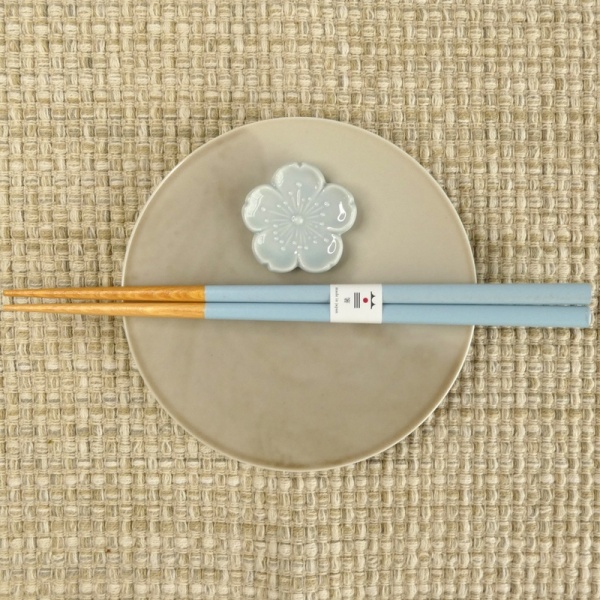 Pastel blue chopsticks and chopstick rest on muted grey plate