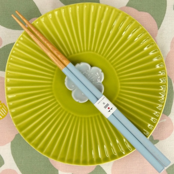 Pastel baby blue chopsticks and chopstick rest on vibrant green plate