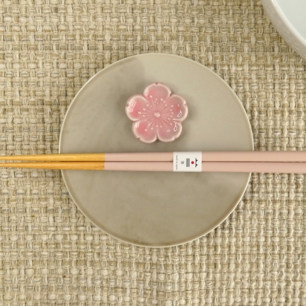 Pastel pale pink chopsticks and chopstick rest on muted grey plate