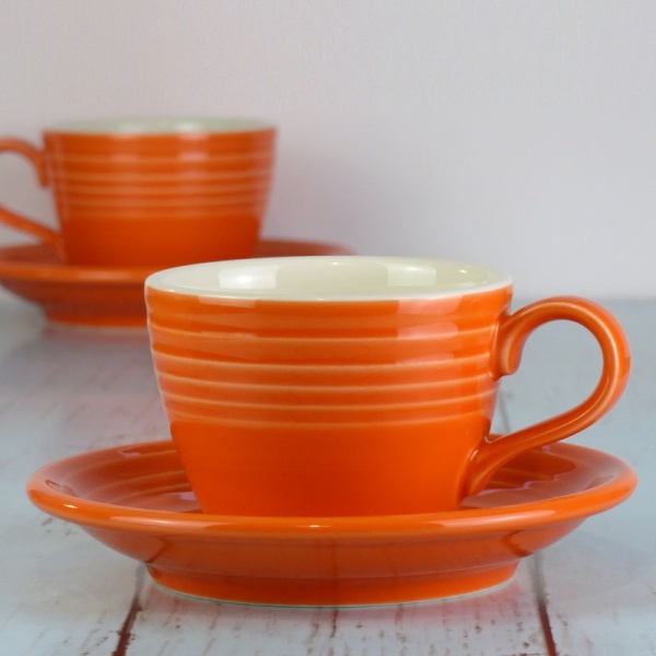 Mandarin orange coffee cup and saucer on pale work surface