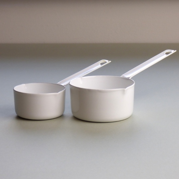 Two white enamel measuring cups