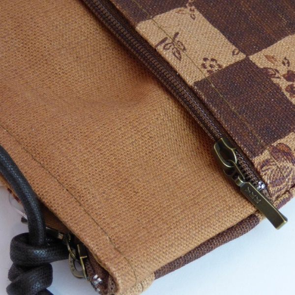 Close up of Pochette style handbag in tan and dark brown with a check design