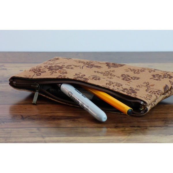 Canvas zip bag with brown floral design in use as a pencil case