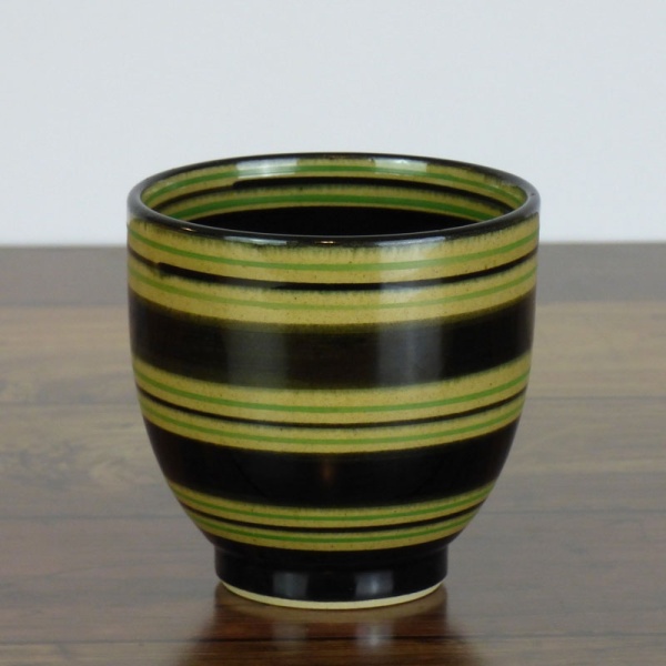 Black Japanese tea cup with green stripe pattern on dark kitchen surface