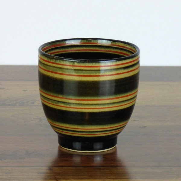 Black Japanese tea cup with red stripe pattern on dark kitchen surface
