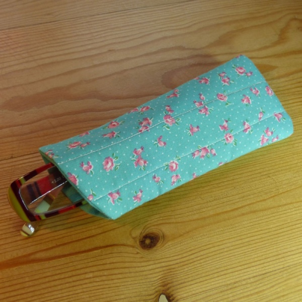 Handmade quilted glasses case in turquoise rose print - shown with glasses