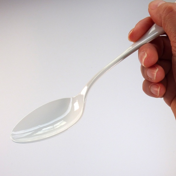 White enamel dessert spoon held in the hand