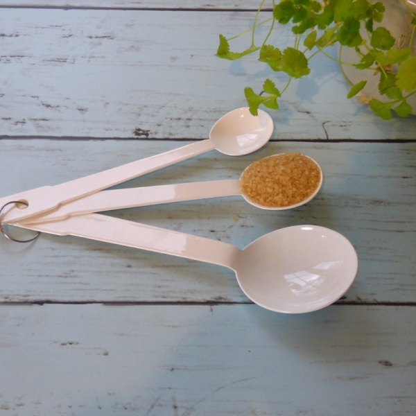 Set of three white enamel measuring spoons on kitchen top
