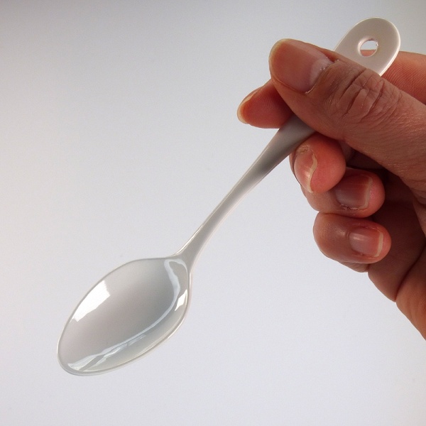White enamelware teaspoon held in the hand