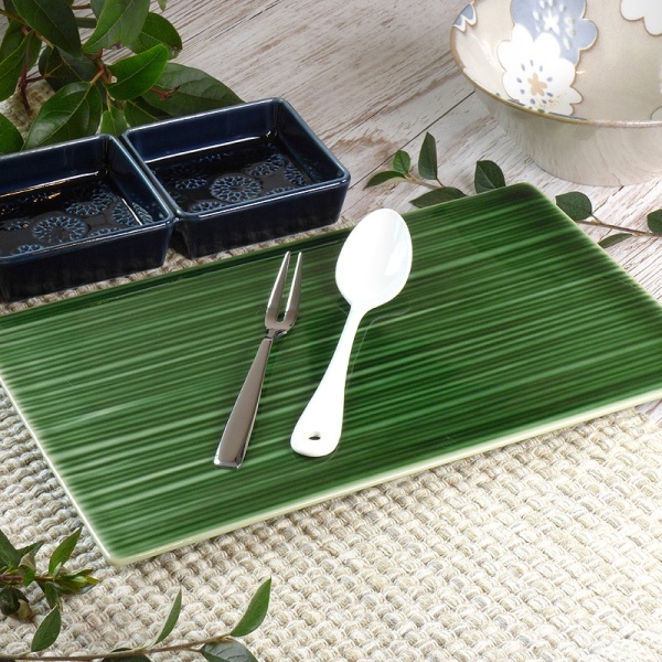 Green rectangular serving platter with spoon and fork