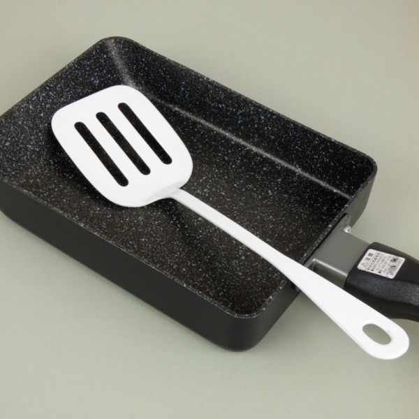 White enamel mini spatula next to tamagoyaki pan