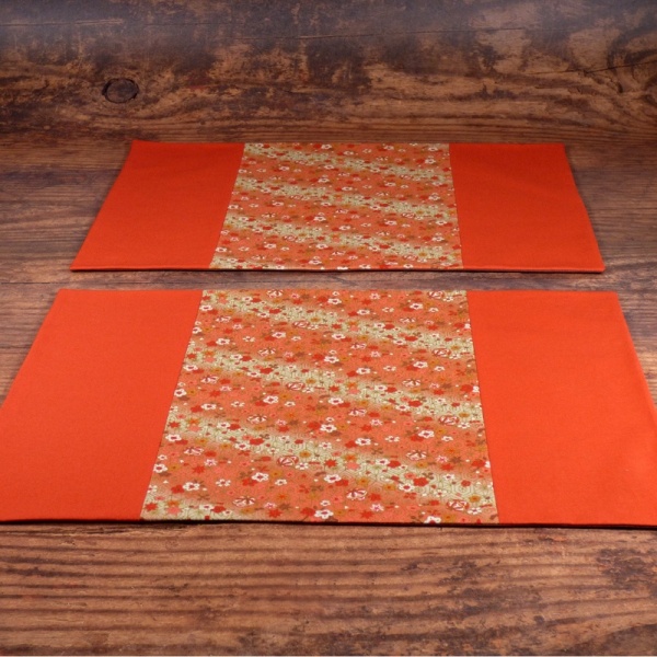 Two orange Flowers & Bells placemat on table