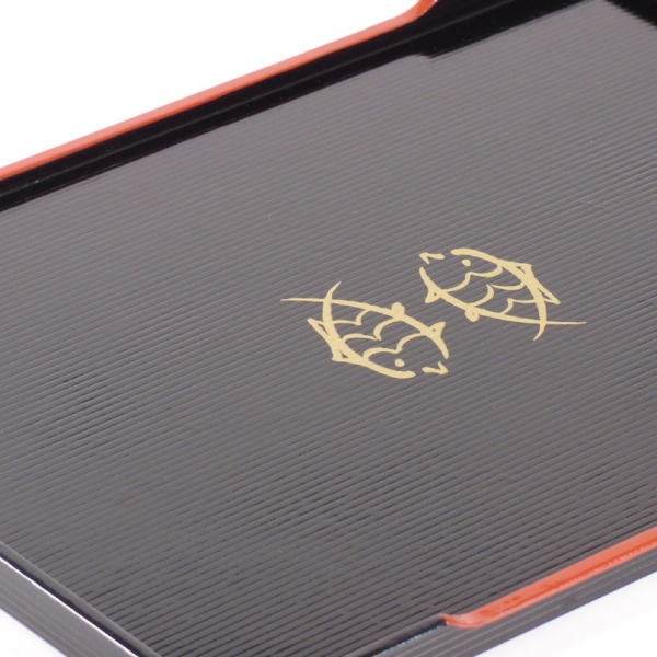 Close up of gold fish decoration on black lacquered tray