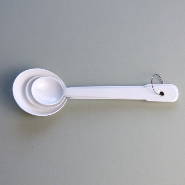 Set of three white enamel measuring spoons nested together
