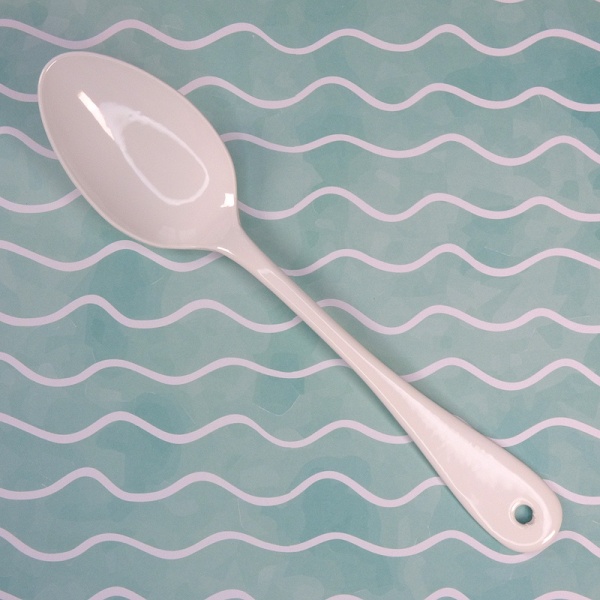 White enamel teaspoon on blue waves background