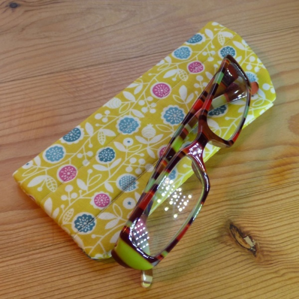 Handmade quilted glasses case in yellow vine floral print - shown with glasses