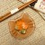 Ginger tabby cat small glass plate with Japanese pickles and chopsticks on table
