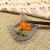 Grey tabby cat small glass plate with Japanese pickles and chopsticks on table