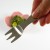 Hand holding mini picnic fork with veggie salad in the background