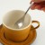 Japanese Tsuchime teaspoon held in hand over a Japanese cup